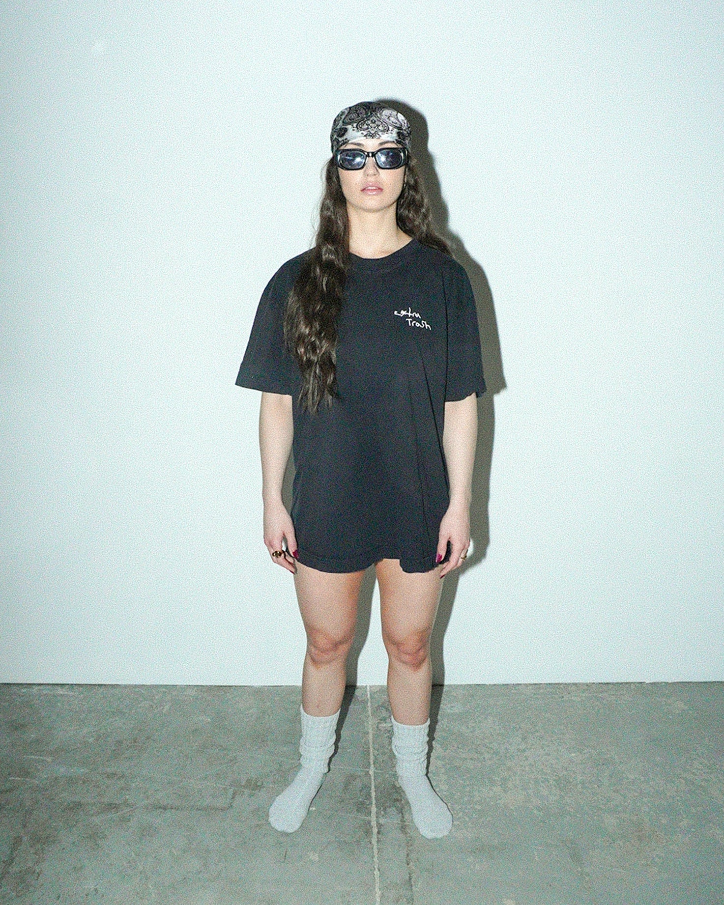 Person wearing a black t-shirt and sunglasses against a plain background