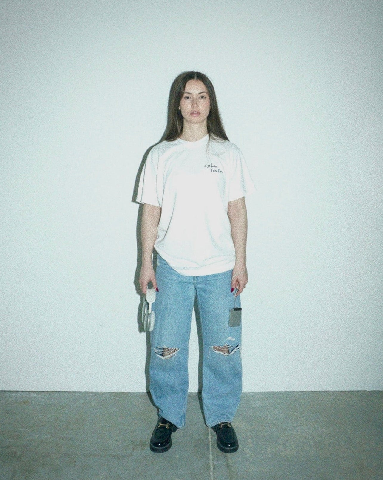 Person wearing a white t-shirt and blue jeans standing against a plain background